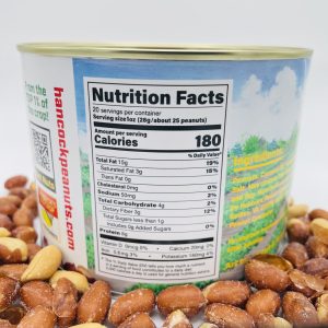 A can of Red Skin Peanuts Hancock Peanut Company sits among loose peanuts. The label shows 180 calories, 15g fat (3g saturated), 5g carbs, and 8g protein per serving. The hancockpeanuts.com website appears on the label.