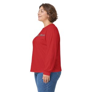 A woman in 17386128689264114578_2048.jpeg stands in profile wearing a red long-sleeve shirt with cursive text across the chest and blue jeans.